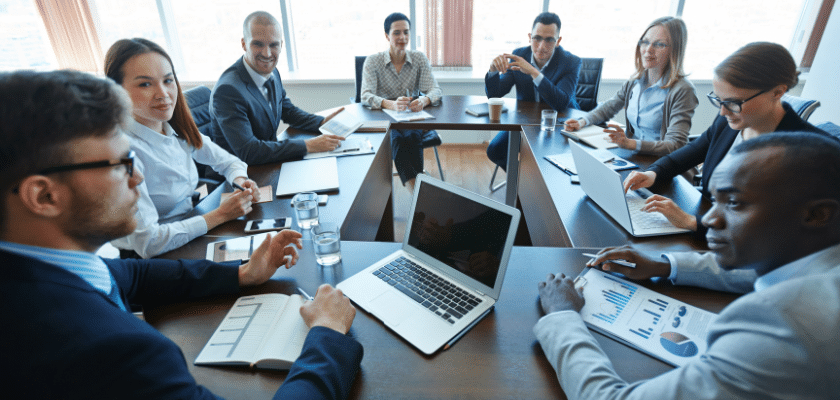 uma sala de reunião com colaboradores, e cada um com seu notebook anotando coisas de trabalho