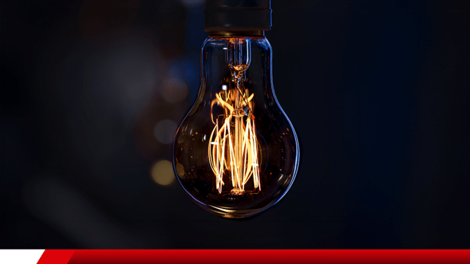 Lâmpada incandescente acesa com filamento visível.
