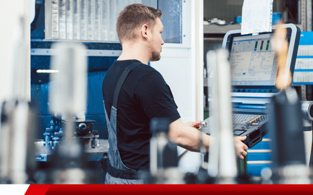 Operador ajustando máquina CNC em ambiente industrial.